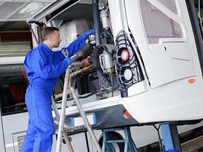 A mechanic servicing a motorcoach engine